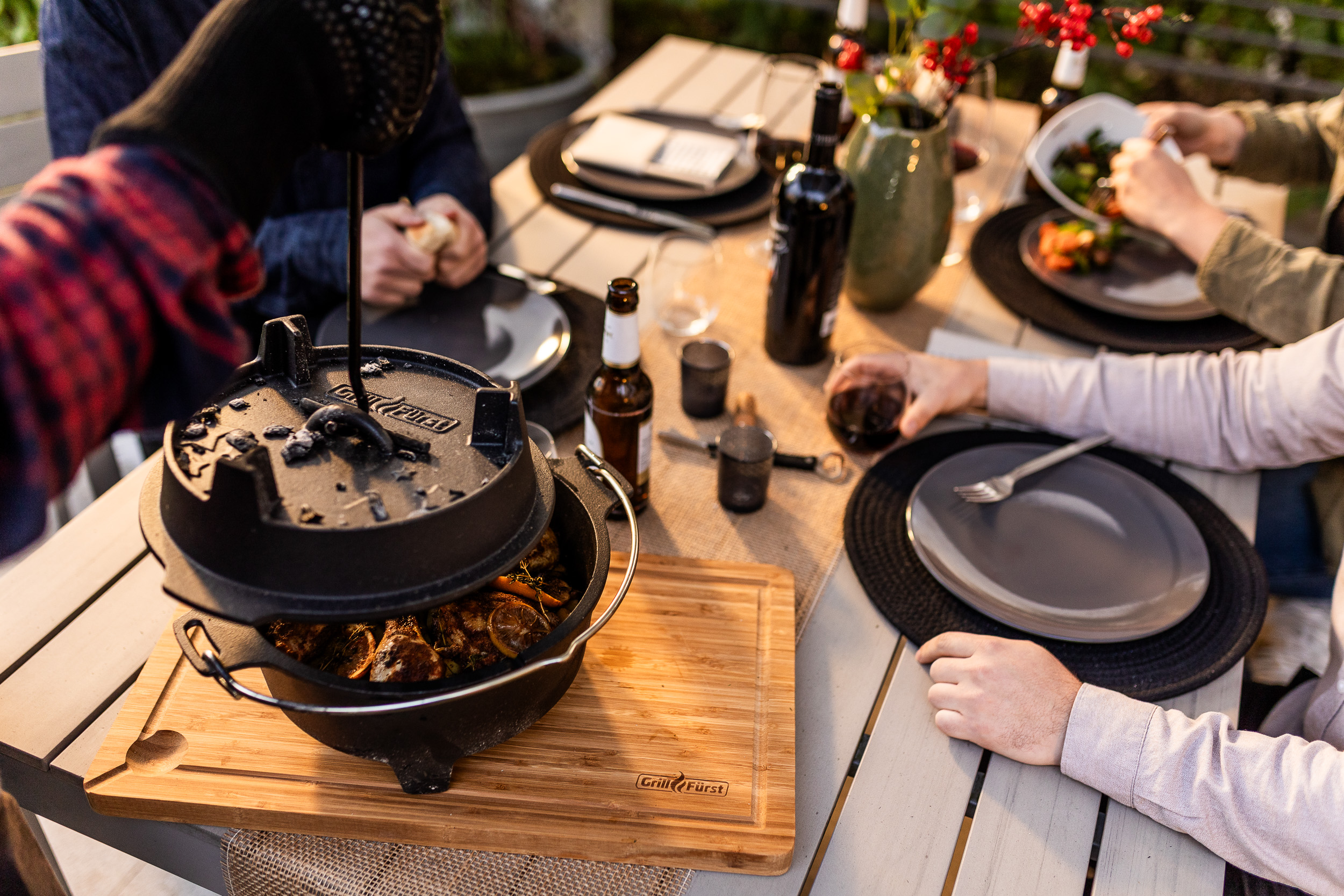 Detailaufnahme Grillzubehör – Contentproduktion für Grillfürst auf einem Tisch steht ein Dutch Oven und Gäste warten