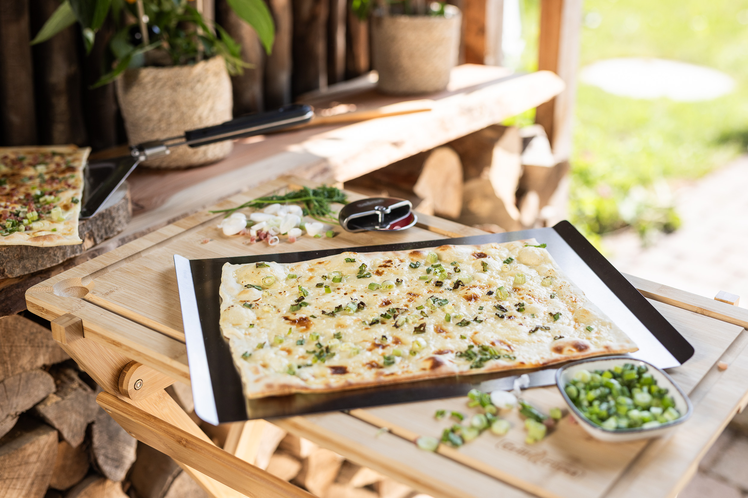On-Location Produktfoto emotional Pizzaschneider mit Flammkuchen und Edelstahlplatte