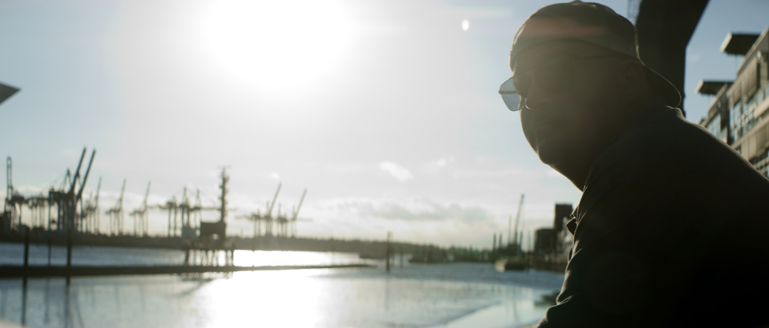 Fahrer eines LKWs am Hamburger Hafen bei Filmproduktion mit Sonne und Wasser im Hintergrund