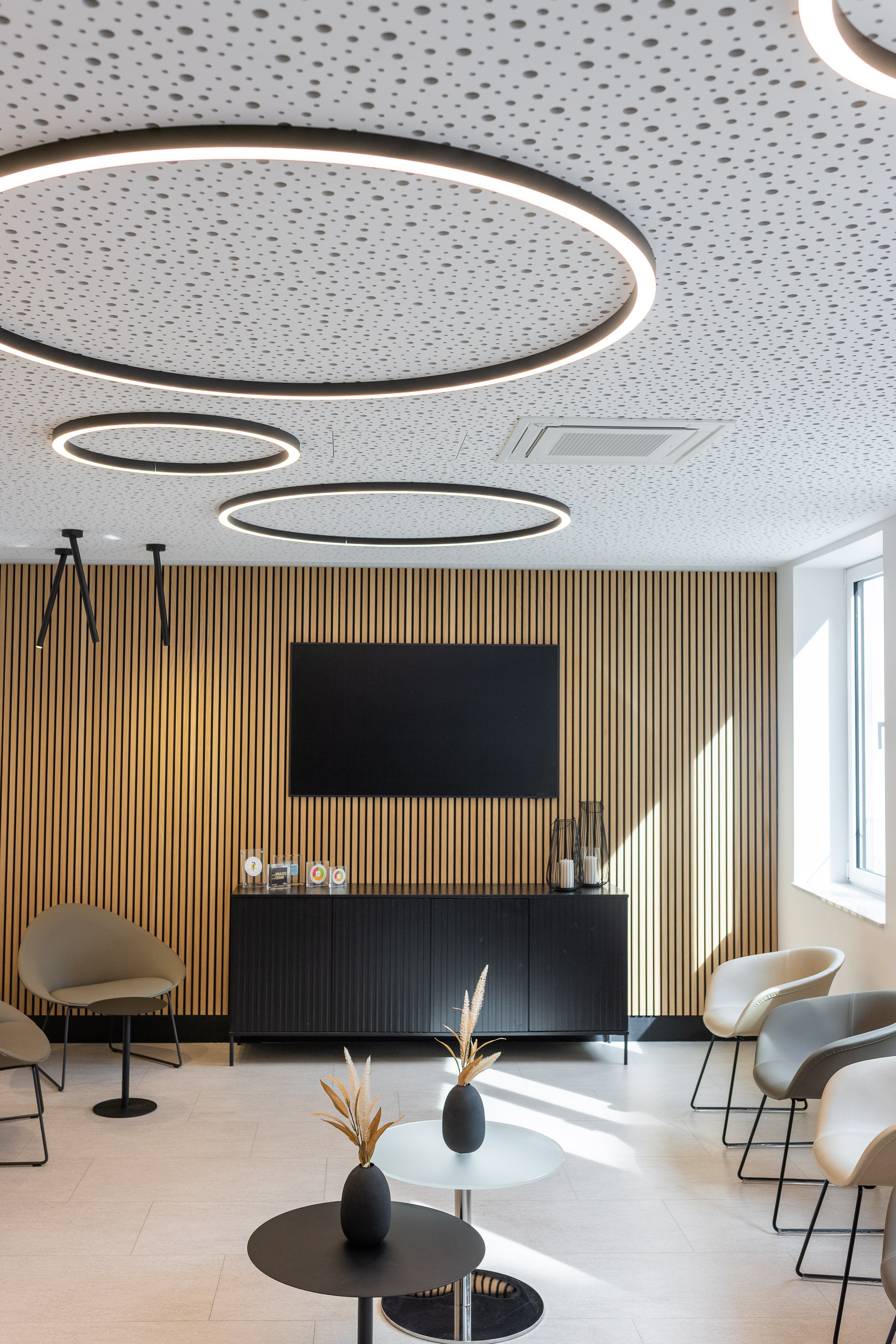 Wartebereich mit Holzverkleidung und Designleuchten in der Kieferorthopädie Dr. Enaia, Fulda