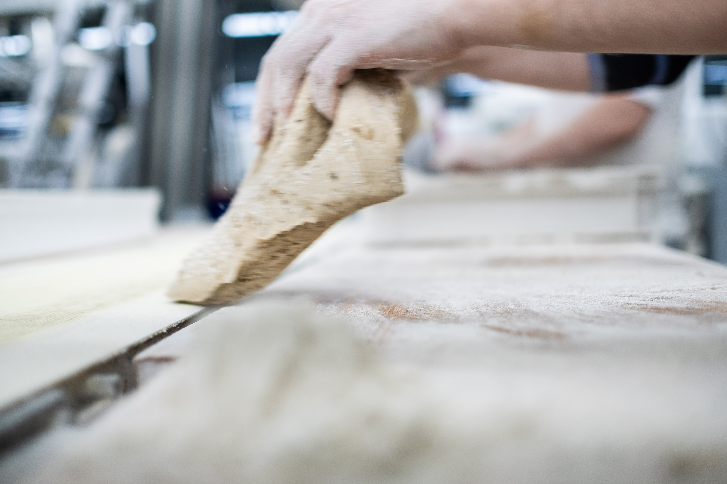 Brot wird gepacken in der Backstube bei Fotoshooting - Teig Rohling während der Verarbeitung