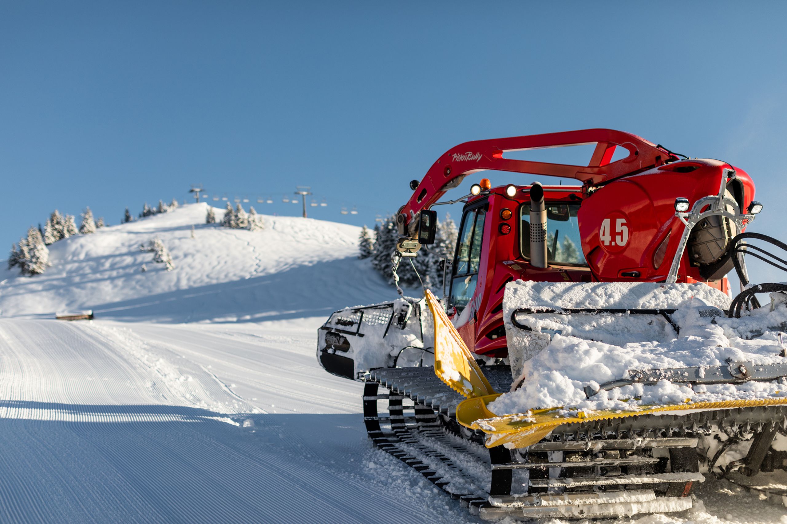 Pistenbully mit Seilwinde krabbelt den Berg hinauf in Skigebiet am Tag - Fotoshooting und FIlmproduktion im Schnee
