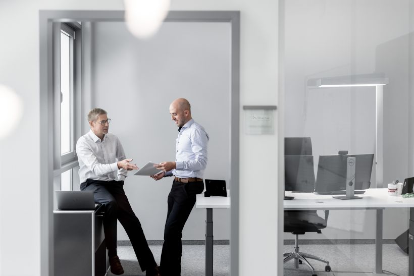 Employer Branding und Werbefotografie - 2 Personen unterhalten sich im Büro und sitzen am Tisch