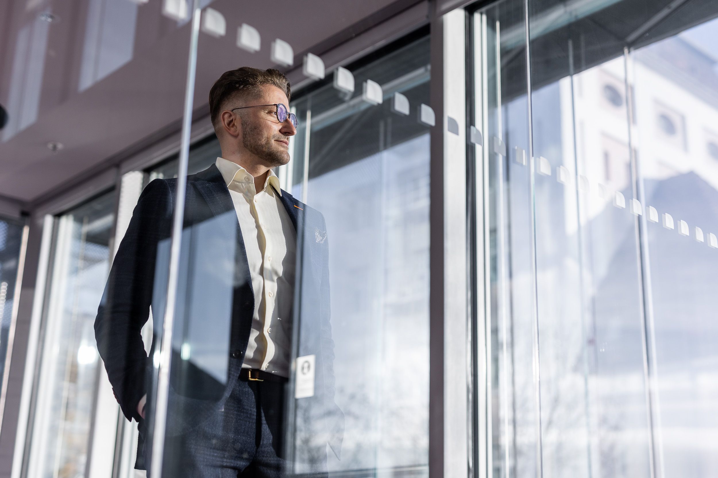 Person steht an Glasscheibe und schaut nach draußen - Business Portrait - Werbefotograf im Rhein Main Gebiet