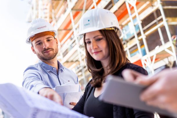 Employer Branding motiv, Mitarbeiter mit Bauleitung weiblich auf Baustelle mit Bauplan - GWH Bauprojekte