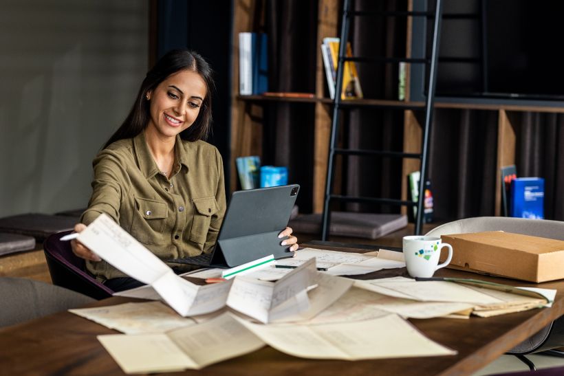 Frau im Büro aus der Bauplanung checkt alte Unterlagen beim Fotoshooting für Employer Branding