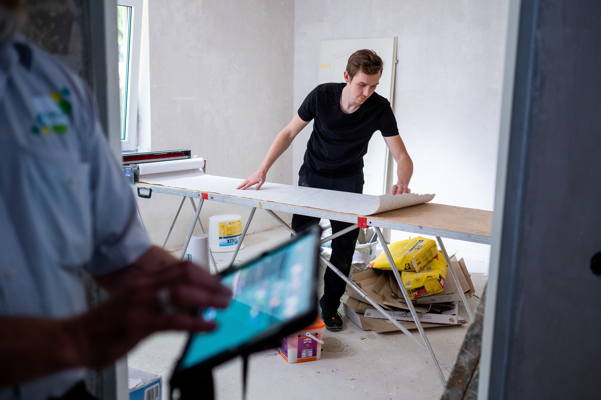 Employer Branding & CI Werbefotografie für Website der GWH in Frankfurt - Person tapeziert und Hausmeister schaut mit Ipad zu