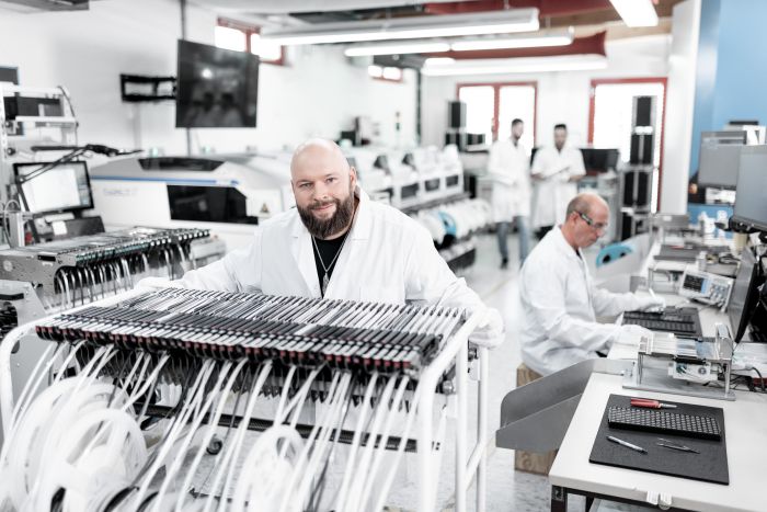CI & Brand Werbefotografie in Frankfurt - Chip und Halbleiter Industrie - Mitarbeiter schiebt wagen durch die Produktion im weißen Kittel mit ESD Outfit