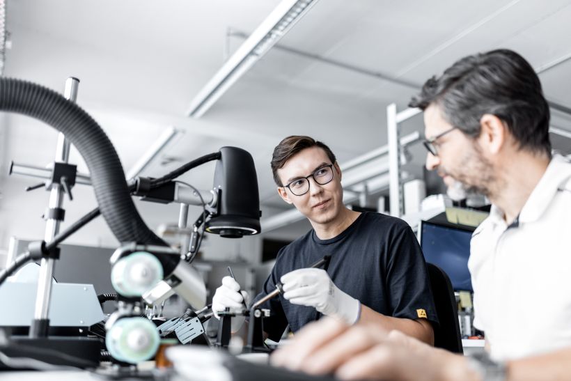 Employer Branding & Recruiting Fotografie in Frankfurt - Nachwuchstalent sitzt mit Vorgesetzten am Tisch und lötet an einem Microchip