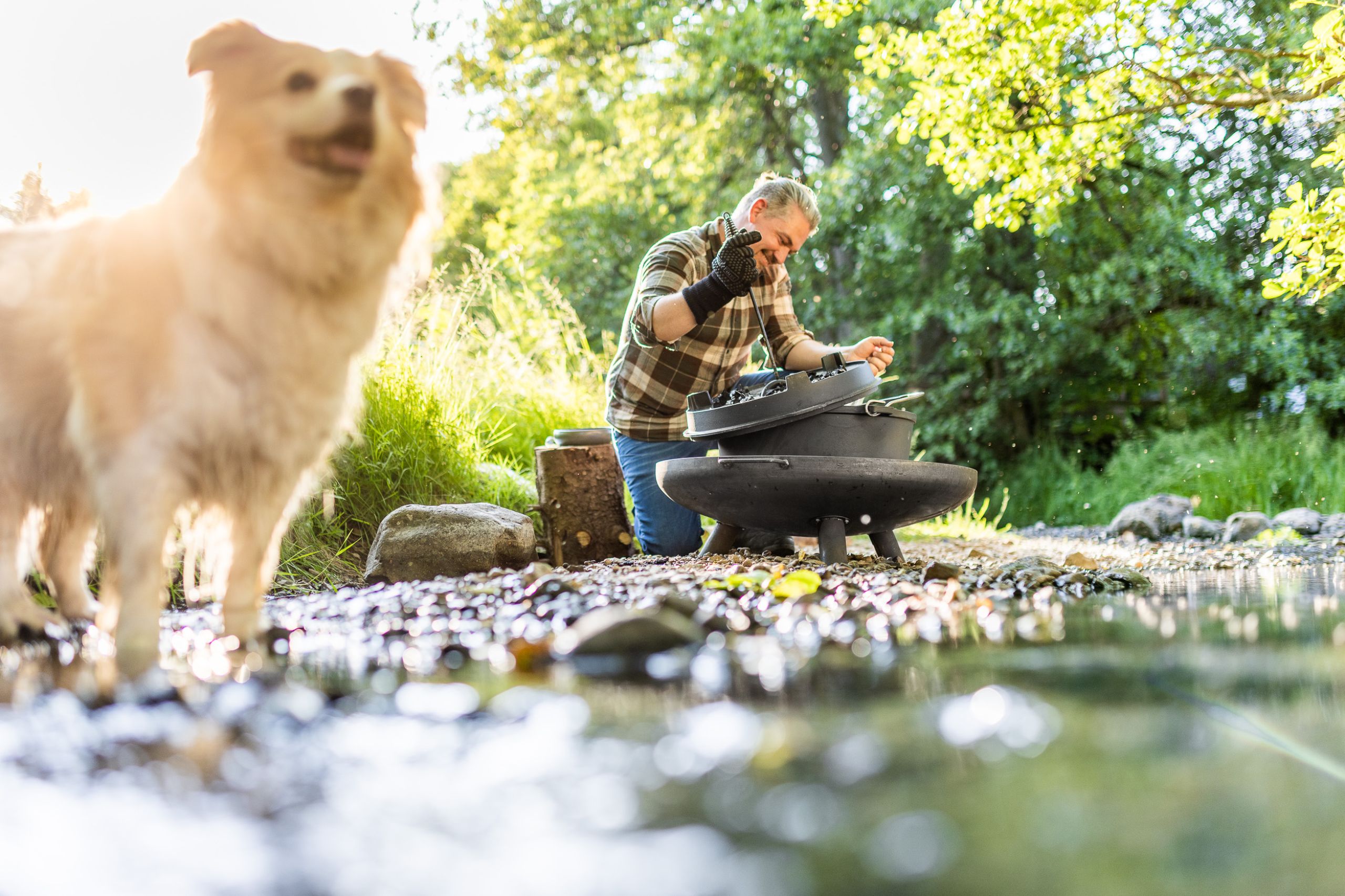 Produktaufnahme On-Location Shooting für Grillhersteller und Onlineshop - Hund und Mann sind im Fluss und Grillen im Dutch Oven